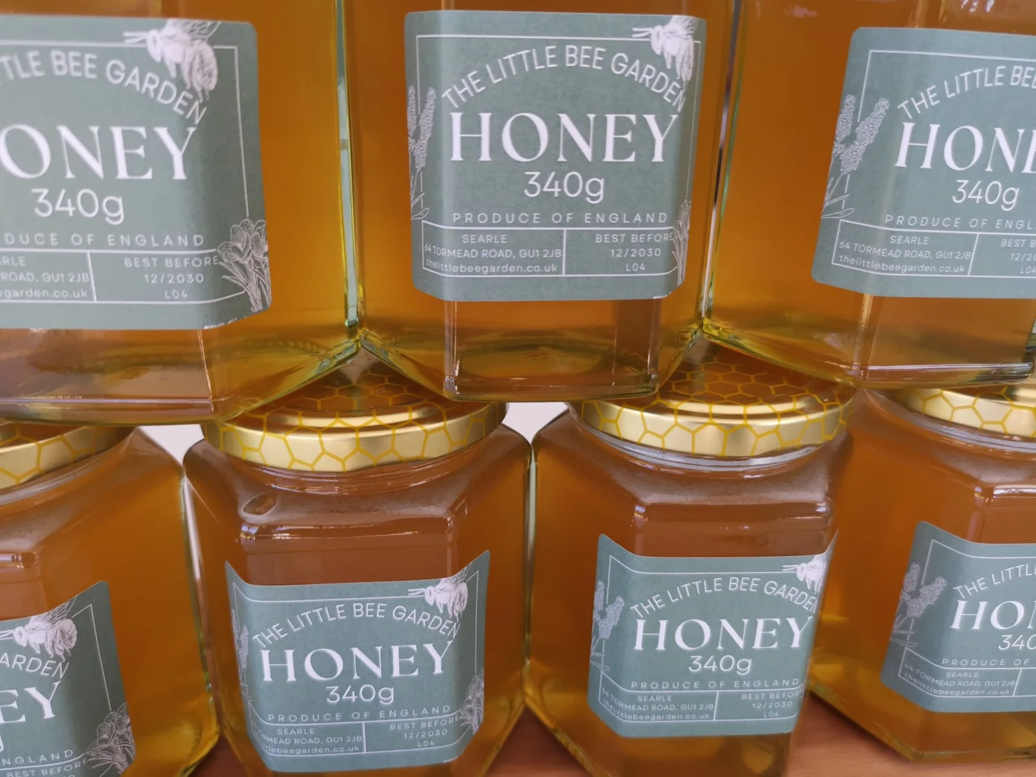 Freshly jarred golden honey with The Little Bee Garden labels